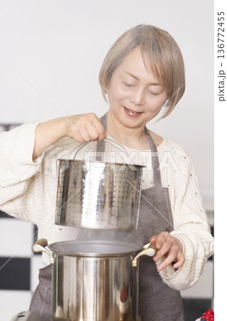 キッチンでパスタを茹でるシニア女性 キッチンでパスタを茹でるシニア女性 136772455