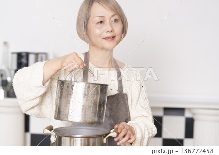 キッチンでパスタを茹でるシニア女性 キッチンでパスタを茹でるシニア女性 136772458