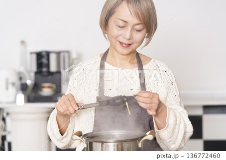 キッチンでパスタを茹でるシニア女性 キッチンでパスタを茹でるシニア女性 136772460