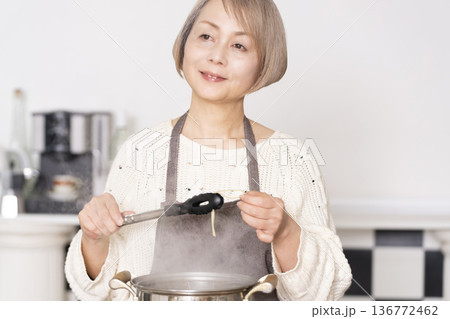 キッチンでパスタを茹でるシニア女性 キッチンでパスタを茹でるシニア女性 136772462