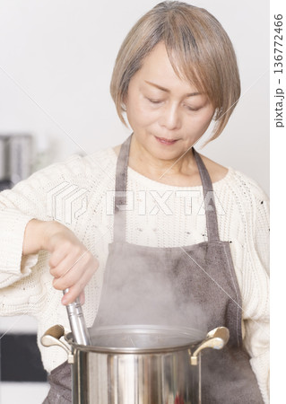 キッチンでパスタを茹でるシニア女性 キッチンでパスタを茹でるシニア女性 136772466