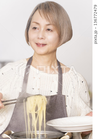 キッチンでパスタを茹でるシニア女性 キッチンでパスタを茹でるシニア女性 136772479