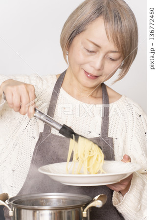 キッチンでパスタを茹でるシニア女性 キッチンでパスタを茹でるシニア女性 136772480