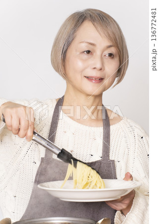 キッチンでパスタを茹でるシニア女性 キッチンでパスタを茹でるシニア女性 136772481
