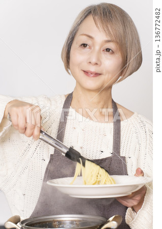 キッチンでパスタを茹でるシニア女性 キッチンでパスタを茹でるシニア女性 136772482