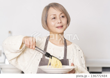 キッチンでパスタを茹でるシニア女性 キッチンでパスタを茹でるシニア女性 136772484