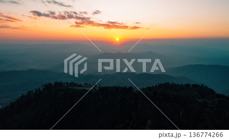 Breathtaking aerial landscape of layered mountains silhouette at golden hour sunset. 136774266
