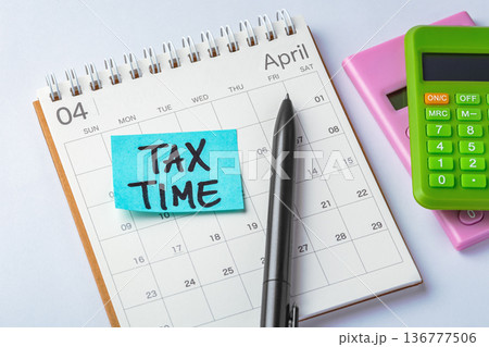 Sticky note with tax time word on calendar with calculators and pen on table, tax payment due, tax season concept 136777506