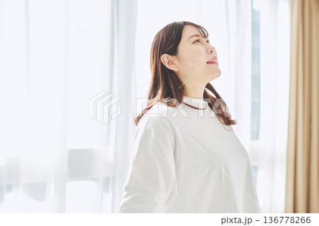 朝の自然光の中で深呼吸をしてリラックスする女性 136778266