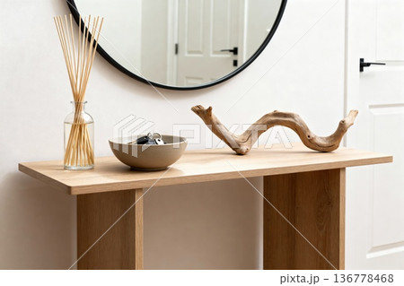 Modern minimalist entryway with round mirror and natural decor on wooden console table 136778468