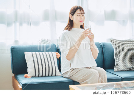 自宅のリビングで水分補給をする健康的な女性 自宅のリビングで水分補給をする健康的な女性 136778660