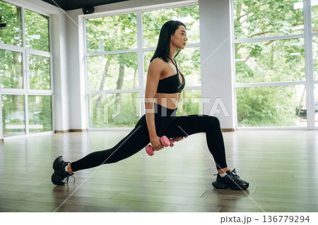 Squats with dumbbells. Woman is doing fitness indoors Squats with dumbbells. Woman is doing fitness indoors 136779294