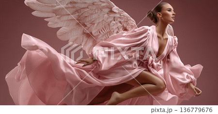 Graceful figure with delicate wings. Celestialinspired fashion portrayal showcasing model with billowing fabric and sculptural wing design 136779676