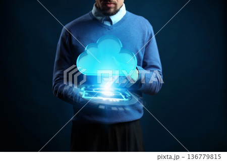 Man interacts with virtual cloud technology using a tablet in dark setting Man interacts with virtual cloud technology using a tablet in dark setting 136779815