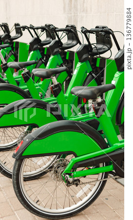 Green bikes lined up in a city bike-sharing station during daylight hours Green bikes lined up in a city bike-sharing station during daylight hours 136779884