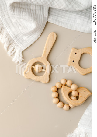 Wooden baby toys are placed on a light surface with a soft cloth nearby 136779885