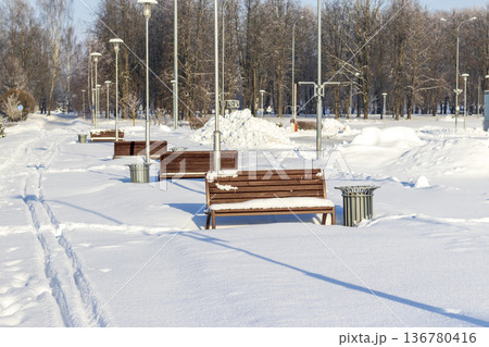 Array of the benches in a park covered with snow 136780416