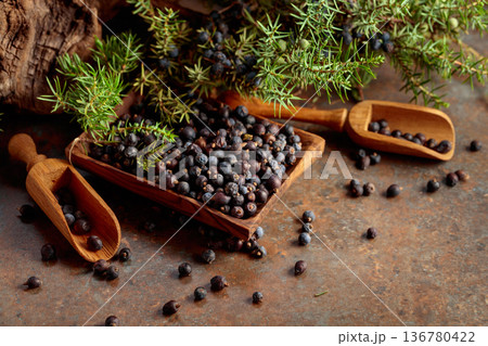 Juniper berries in wooden dish and green branches. Juniper berries in wooden dish and green branches. 136780422