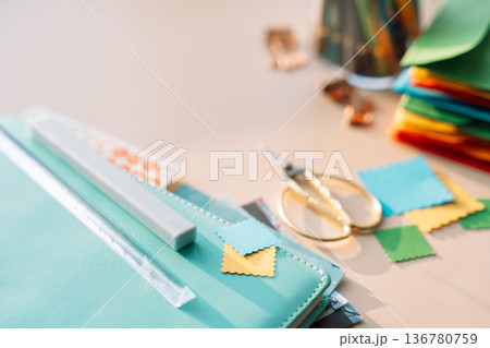 Close up of planner supplies with scissors and colorful paper squares on pastel desk, minimal creative workspace Close up of planner supplies with scissors and colorful paper squares on pastel desk, minimal creative workspace 136780759