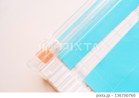 Paper trimmer cutting blue paper sheet, craft tool close up on pastel background with copy space 136780760