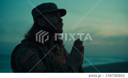 Silhouette of an American soldier praying for veteran to God on the beach night 136780802