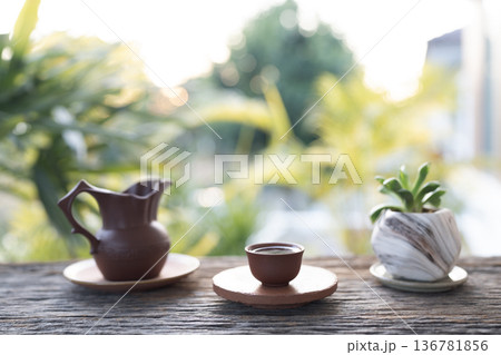 Old vintage Earthenware pottery tea set and potted plant arranged on old wooden table 136781856