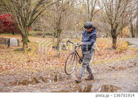 Man carrying bicycle on muddy autumn path after rain Man carrying bicycle on muddy autumn path after rain 136781914