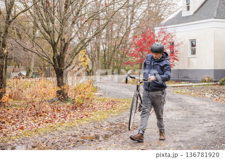 Man carrying bicycle on muddy road after rain in autumn Man carrying bicycle on muddy road after rain in autumn 136781920