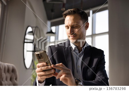 Positive handsome Hispanic CEO man using online business application 136783298