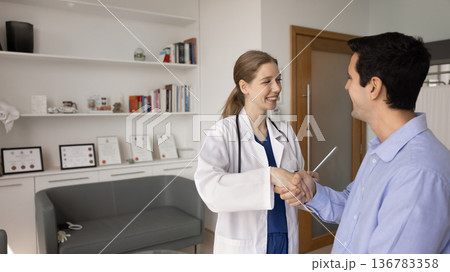 Happy man, private clinic patient shaking hands with female nurse Happy man, private clinic patient shaking hands with female nurse 136783358