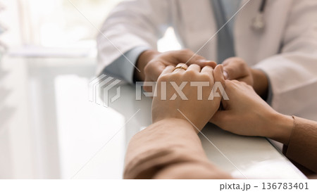Kind doctor holding hands of female patient at medical meeting Kind doctor holding hands of female patient at medical meeting 136783401