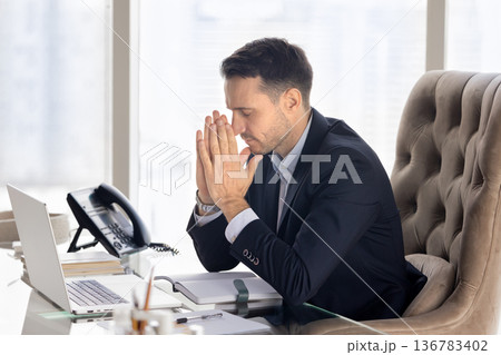Religious business executive man praying at office workplace Religious business executive man praying at office workplace 136783402
