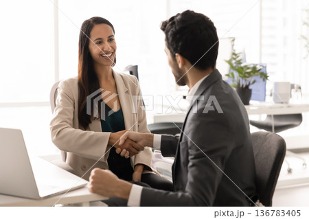 Happy professional woman shaking hands with male client 136783405