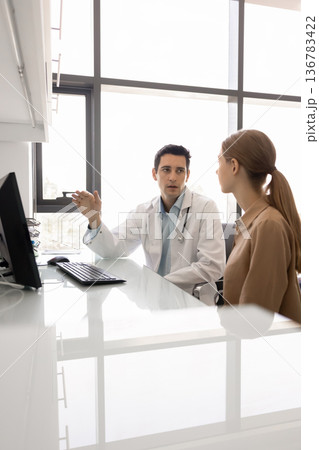 Young GP lead talk with female patient in clinic Young GP lead talk with female patient in clinic 136783422