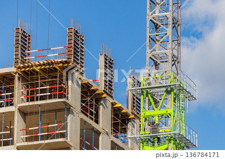 Construction site showing cranes and concrete structure against a blue sky Construction site showing cranes and concrete structure against a blue sky 136784171