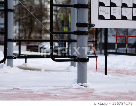 Colorful playground equipment stands in the snow, inviting fun and laughter on a chilly winter day Colorful playground equipment stands in the snow, inviting fun and laughter on a chilly winter day 136784179