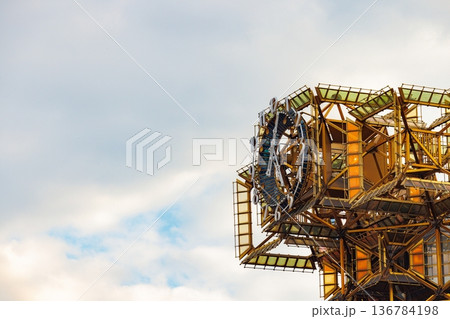 Glistening metal structure reflects the sky at dusk in an artistic display of modern engineering Glistening metal structure reflects the sky at dusk in an artistic display of modern engineering 136784198