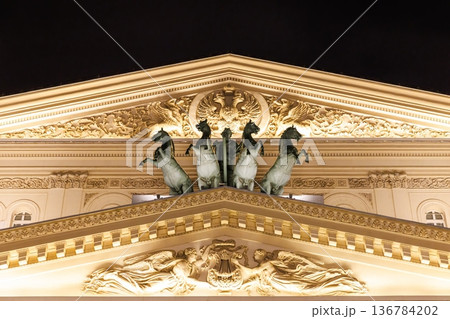 Majestic horses adorn the stunning rooftop of an iconic theater illuminated at night 136784202