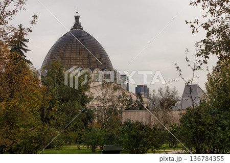 Dome structure rises above lush greenery in a serene city park during a cloudy afternoon Dome structure rises above lush greenery in a serene city park during a cloudy afternoon 136784355