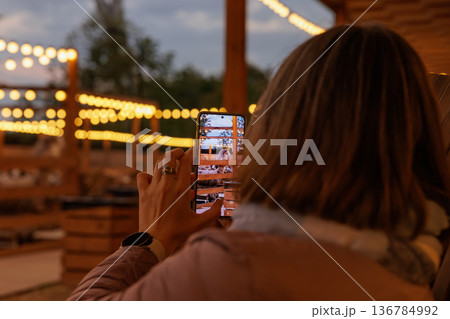 Capturing the golden glow of string lights at an evening gathering outdoors with friends Capturing the golden glow of string lights at an evening gathering outdoors with friends 136784992