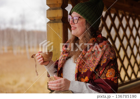 Warm autumn moments enjoyed by a smiling woman with a cup in a rustic setting Warm autumn moments enjoyed by a smiling woman with a cup in a rustic setting 136785190