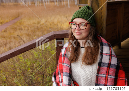 Cozy autumn afternoon spent outdoors with a warm blanket and peaceful nature surroundings Cozy autumn afternoon spent outdoors with a warm blanket and peaceful nature surroundings 136785195