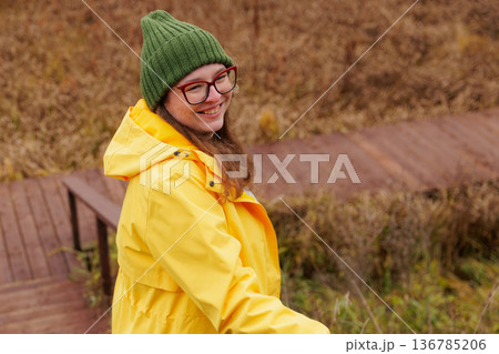 Joyful moments in a cozy yellow raincoat during autumn stroll in a serene park setting 136785206