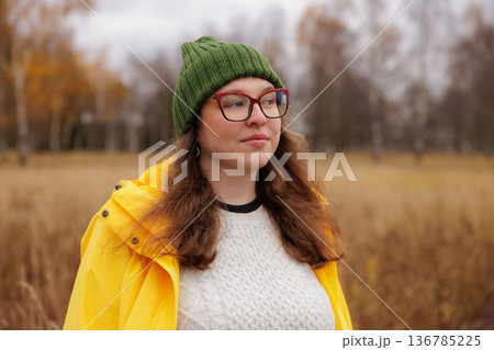 Bright yellow coat and green hat bring warmth to a chilly autumn day in the park Bright yellow coat and green hat bring warmth to a chilly autumn day in the park 136785225