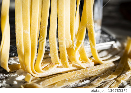 Fresh raw noodles made on home pasta machine closeup low angle view Fresh raw noodles made on home pasta machine closeup low angle view 136785373