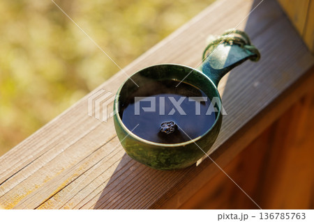 Warm cup of tea resting on wooden balcony, wisps of steam dancing in the soft morning light 136785763
