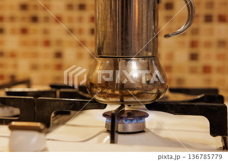 Brewing coffee on a stovetop using a traditional moka pot in a cozy kitchen setting 136785779