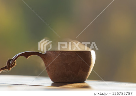 Warm steam rising from a cozy cup on a tranquil morning by the window in nature's embrace 136785787