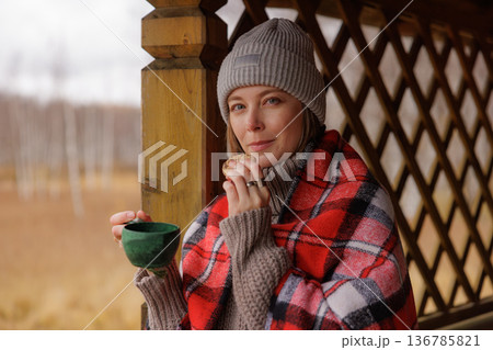 Enjoying a warm drink and a cookie while wrapped in a cozy blanket on a chilly day in a beautiful natural setting Enjoying a warm drink and a cookie while wrapped in a cozy blanket on a chilly day in a beautiful natural setting 136785821