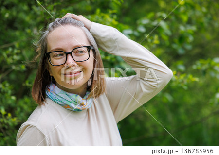 Smiling woman enjoys a sunny day outdoors surrounded by lush greenery Smiling woman enjoys a sunny day outdoors surrounded by lush greenery 136785956